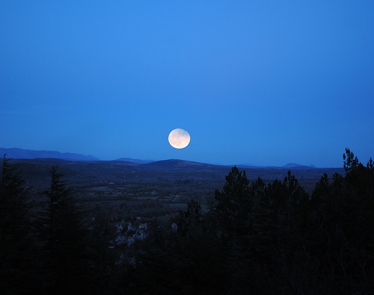 Ici • En fin d’éclipse, la pleine lune se lève au-dessus du plateau du Larzac, Le Caylar, Hérault, France, 10 décembre ‎2011